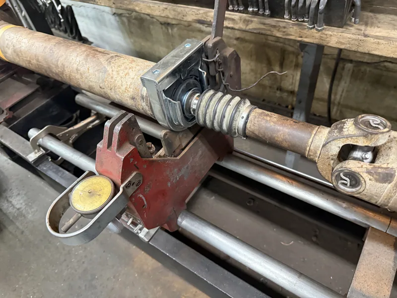 Long driveline assembly set up on shop equipment during repair work