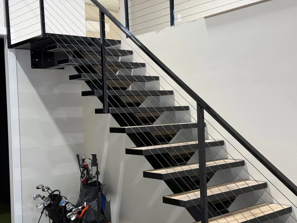 Completed black steel staircase with cable railing and wood stair treads