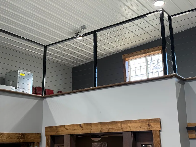 Completed black steel cable railing around an interior upper level