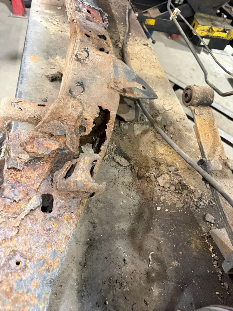 Removed rust-damaged truck frame section showing extensive metal loss