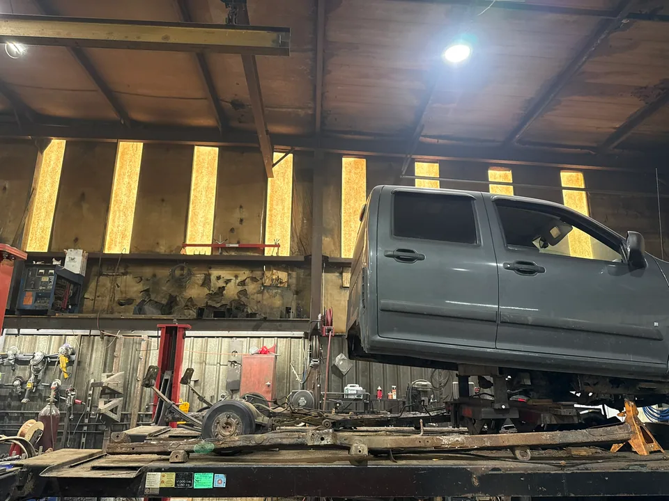 Pickup body supported above its separated rust-damaged frame during reconstruction