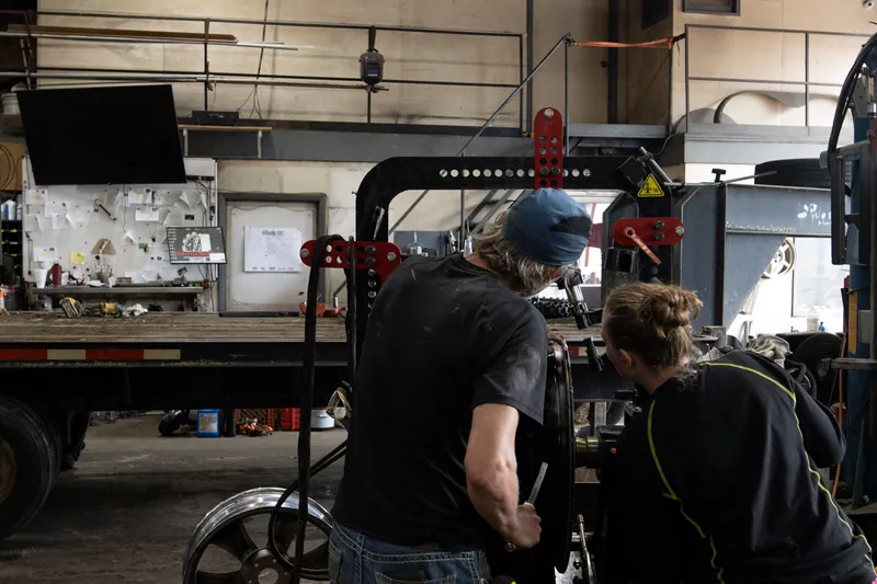 Two shop workers inspecting a wheel in dedicated straightening equipment